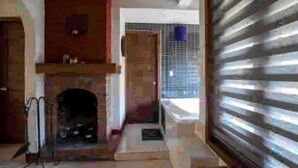 A room with a fireplace, a door leading to another room, and a window with blinds. - Perfect for honeymoon C10 (Lázaro Cárdenas)