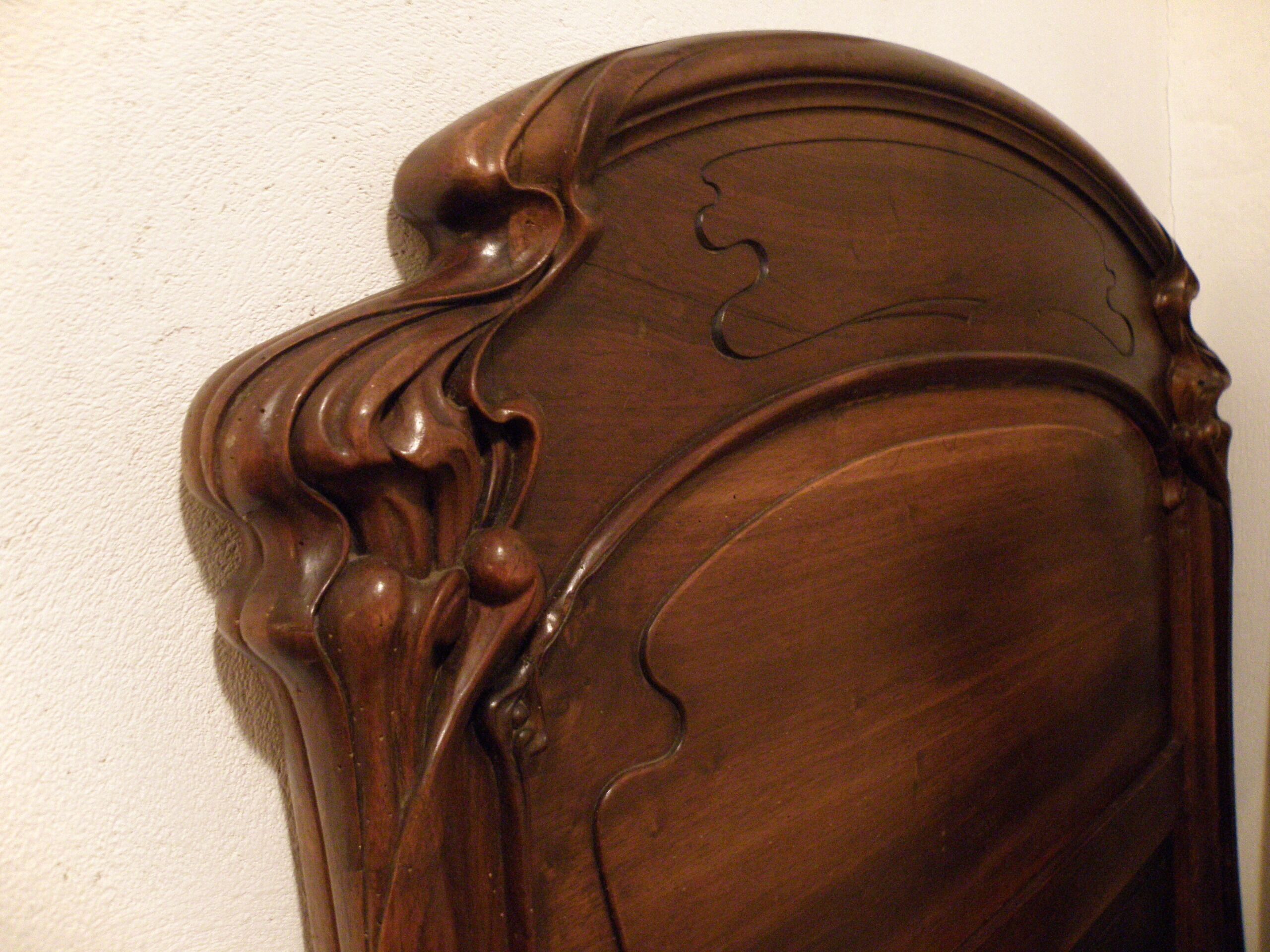 A close-up of a wooden headboard with intricate carvings.