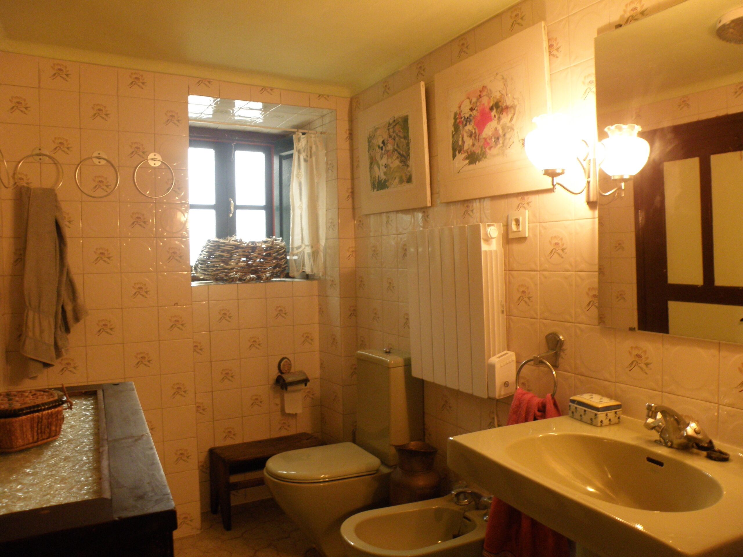 Un baño con inodoro, bidé, lavabo y ventana con vistas.