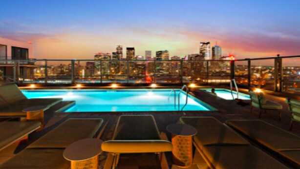 A rooftop pool with lounge chairs and a city skyline view. - NEW!!Denvers ONLY centralTrain HUB "union station", downtown upscale living! (Denver)