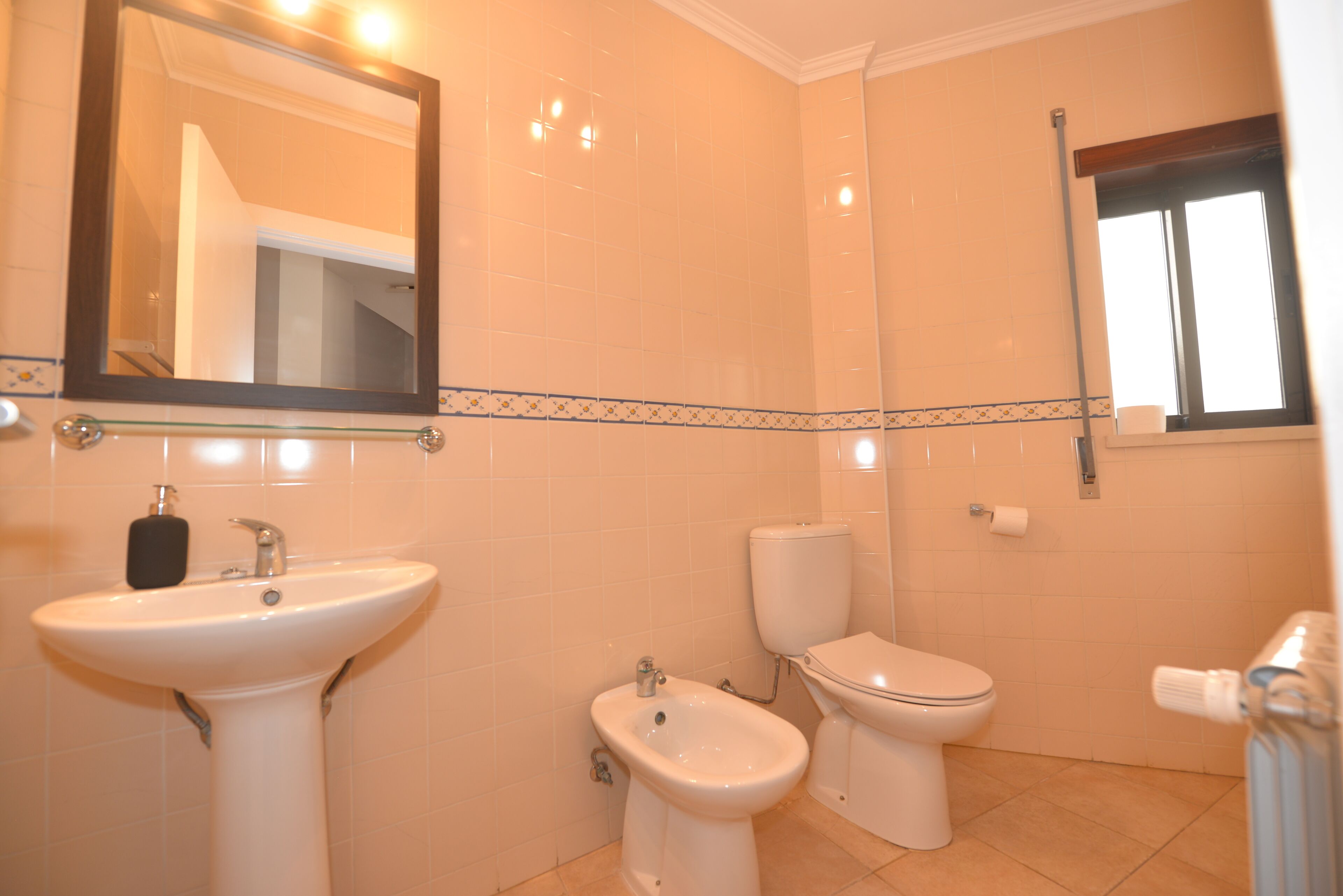 A bathroom with a sink, bidet, toilet, and a mirror.