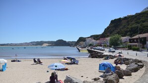 Una platja amb ombrel·les, roques i vista al mar.