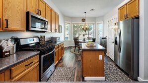 A modern kitchen with wooden cabinets, stainless steel appliances, and a central island. - Relaxing Vacation with Catalina Views & EV Charging 21315404 (Tucson)