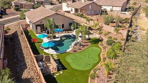 A residential area with a large house featuring a swimming pool, a golf course, and a well-maintained lawn. - Relaxing Vacation with Catalina Views & EV Charging 21315404 (Tucson)