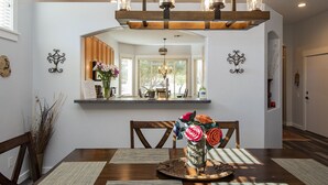 A dining area with a wooden table, chairs, a vase of flowers, and a chandelier. - Relaxing Vacation with Catalina Views & EV Charging 21315404 (Tucson)
