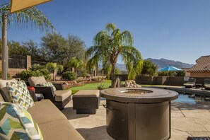 A patio area with outdoor furniture, a fire pit, and a pool.