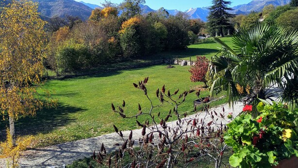 A lush garden with a stone pathway, surrounded by trees with autumn foliage and a mountain backdrop. - Chez Bonjour: holiday home with large terrace overlooking the mountains (Villar Pellice (TO))