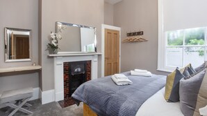 A bedroom with a bed, a fireplace, a mirror, and a window. - Bootham Luxury Apartments Flat 2 (York)