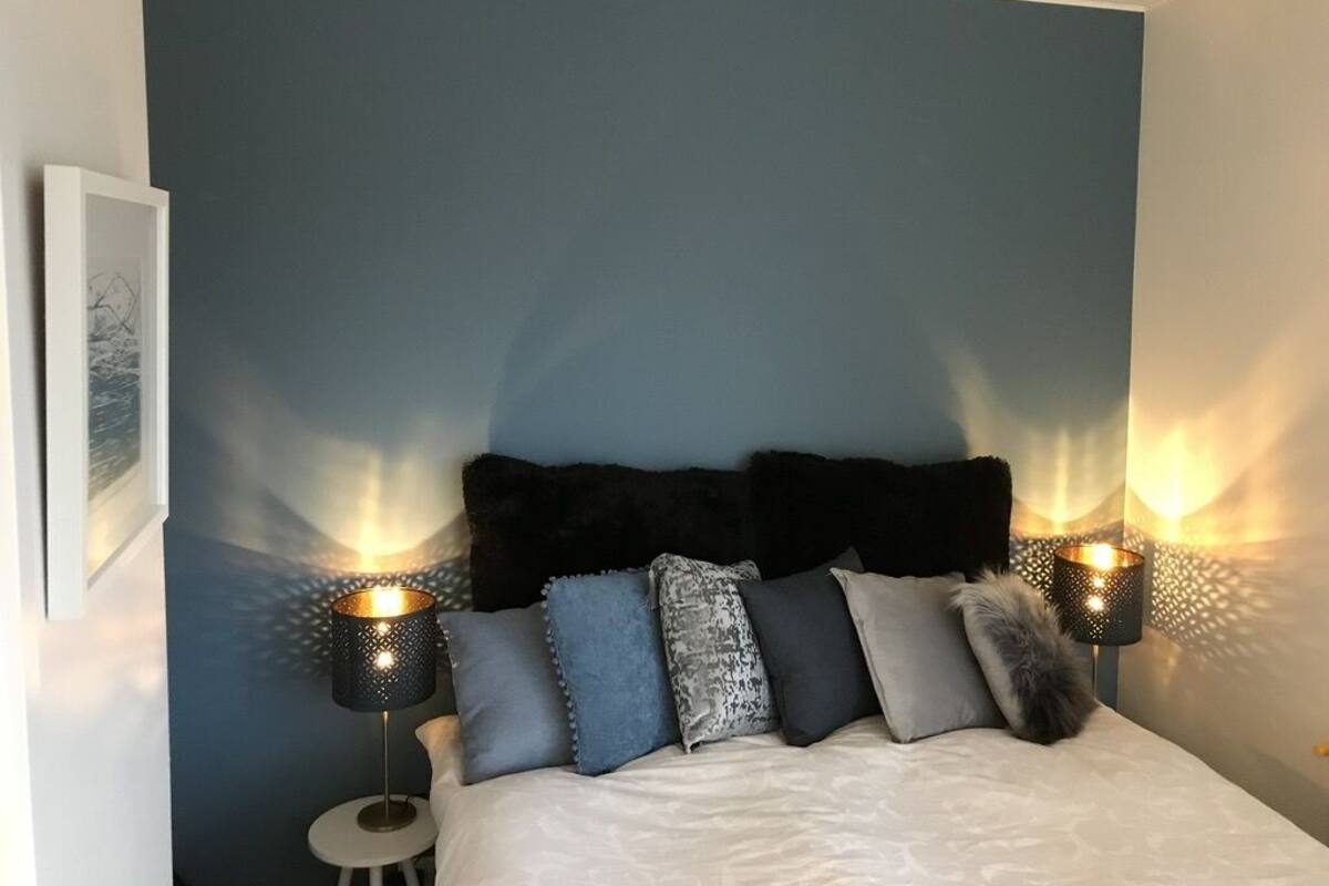 Een slaapkamer met een bed, hoofdeinde en twee wandlampen.