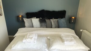 A neatly made bed with two pillows and two folded towels.