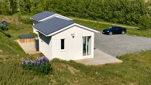 A modern house with a sloped roof, a carport, and a garden with purple flowers.