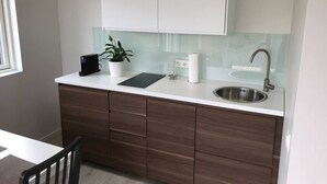 A modern kitchen with white cabinets, a stainless steel sink, and a black countertop.