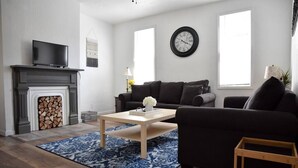 Una sala de estar con chimenea, sofá, mesa de centro y televisor.