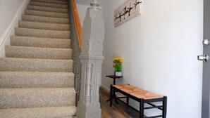 Una escalera con peldaños alfombrados, barandilla de madera y un cuadro colgado en la pared con la imagen de un ave.