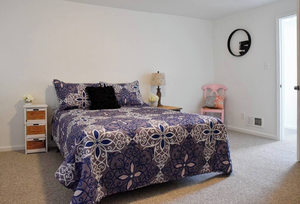 A bedroom with a bed, a nightstand, a lamp, a chair, and a dresser.