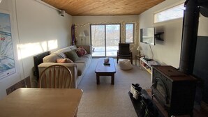 A cozy living room with a wooden ceiling, a sofa, a table, a TV, and a fireplace.
