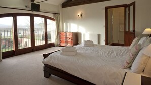 A bedroom with a large bed, a wooden wardrobe, a radiator, and a view through a glass door. - Kestrel Barn, Sleeps 10+2 (5 Bedrooms) (Norfolk)
