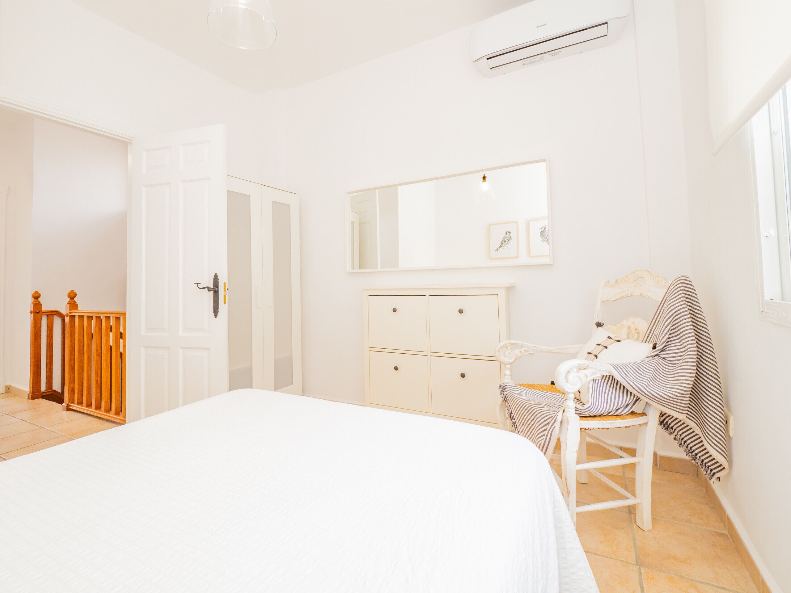 A bedroom with a bed, a dresser, a chair, and a mirror.