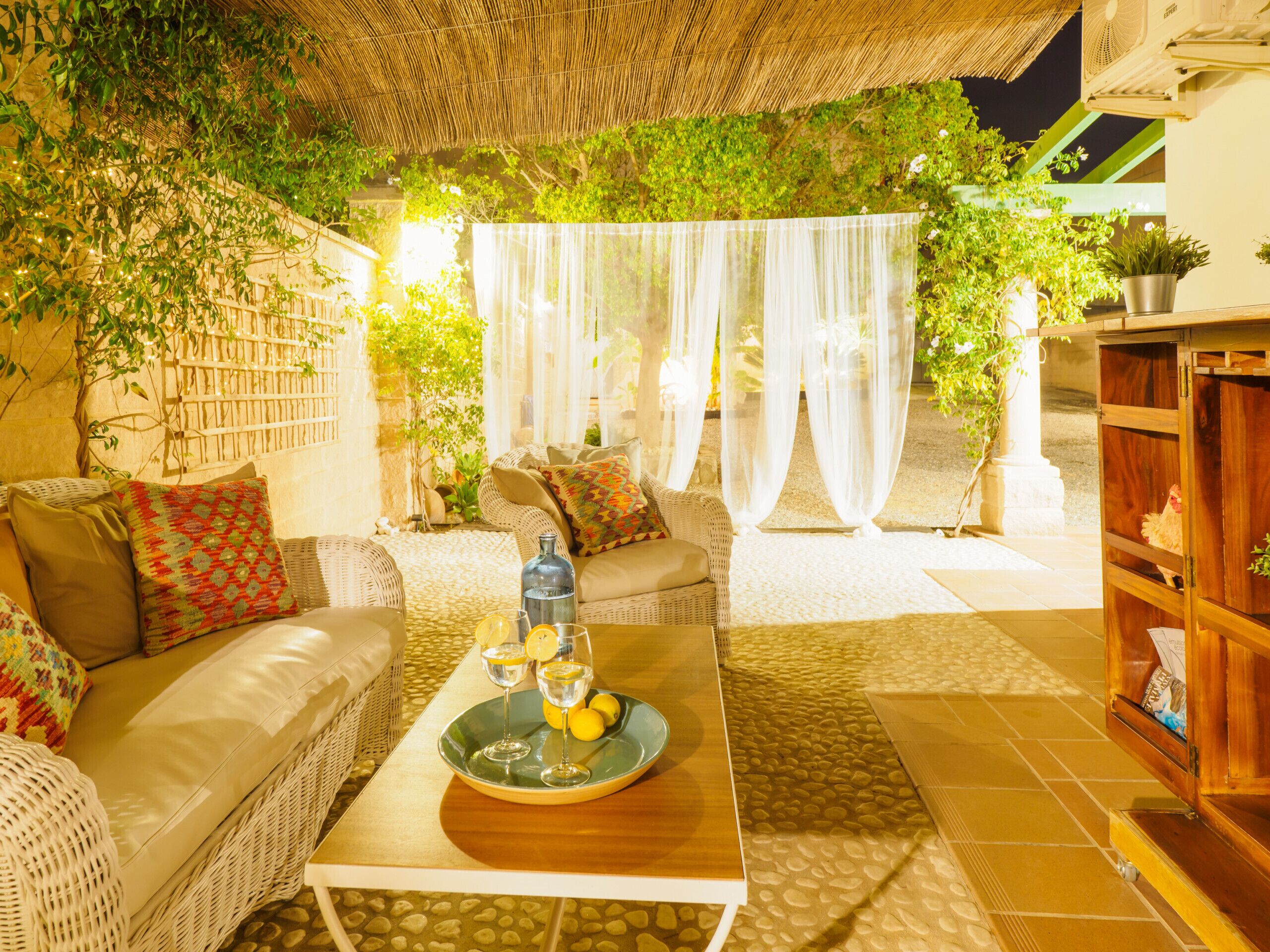 A cozy outdoor seating area with wicker furniture, a table with drinks, and a thatched roof.