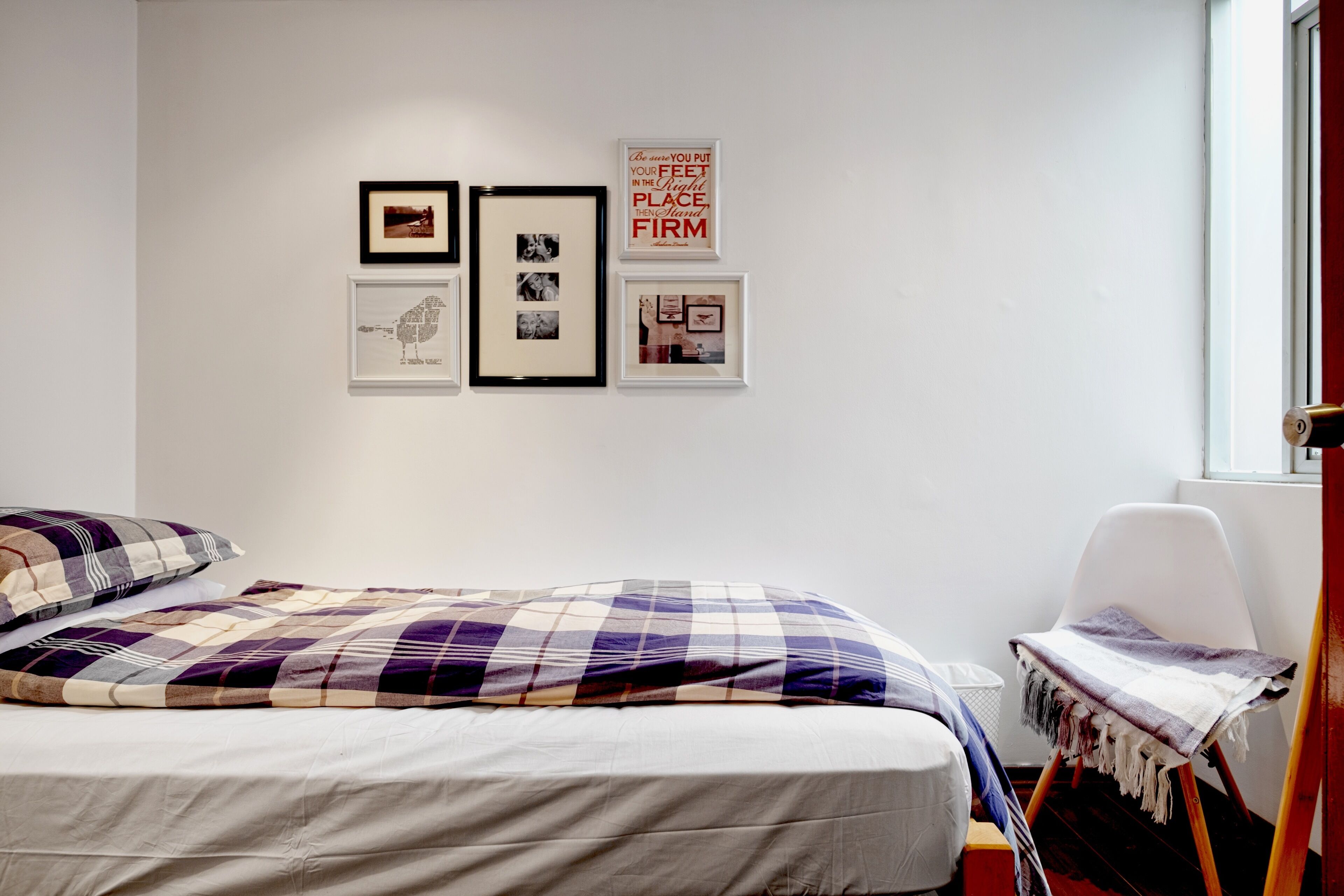 A bedroom with a bed, a chair, and wall art.