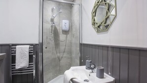 A bathroom with a shower, a sink, and a towel rack. - Sleeps 6 guests  in 2 bedrooms (York)