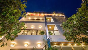 A multi-story hotel with illuminated windows and a modern architectural design. - Brother Villa Hoi An (Da Nang)
