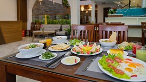 A dining table with various dishes, including a bowl of soup, plates of salad, and a plate of eggs. - Brother Villa Hoi An (Da Nang)