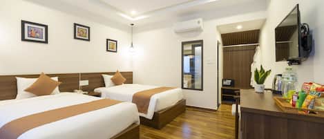 A hotel room with two beds, a desk with a TV, and a bathroom visible through an open door.