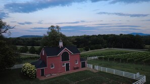A red barn with a white fence, surrounded by green fields and trees. - Ramsay Estate Cottage – Historic Vineyard Retreat with Mountain Views (Greenwood)