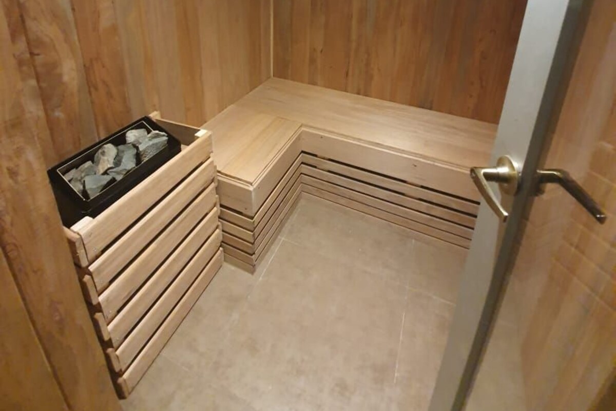 A wooden-paneled room with a bench, a small electrical outlet, and a door.
