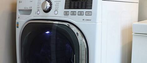 A front-loading white washing machine with a control panel, a transparent door, and a white towel on top.