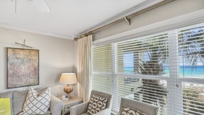 A living room with a sofa, armchairs, a lamp, and a painting on the wall. - Beach-side, beautiful low-rise with uncrowded beach! (Destin)