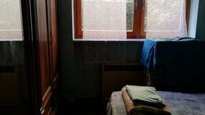 Une chambre avec deux lits, une armoire en bois et une fenêtre donnant sur l’extérieur.