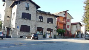 Un bâtiment en pierre de deux étages, avec un panneau indiquant un parking, une petite voiture et un passage piéton.