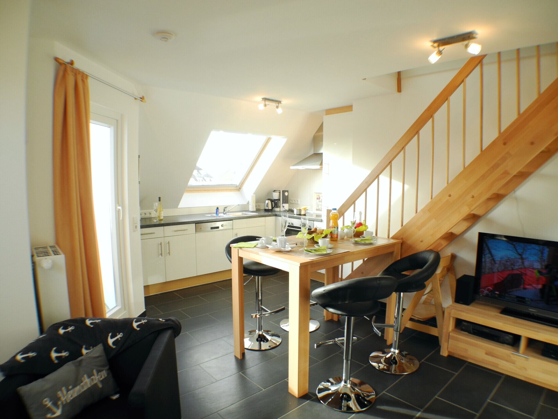Eine Küche mit Essbereich, einem Fernseher und einer Treppe.