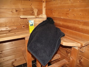 Una sala de sauna con paredes de madera, un banco y una toalla.