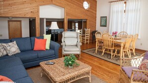 A spacious living room with a blue sofa, a white armchair, and a dining area with wooden chairs and a table.