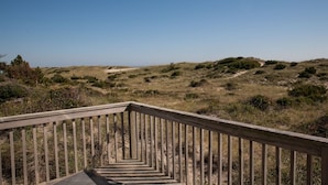 A wooden staircase leading to a beach area with a clear sky.