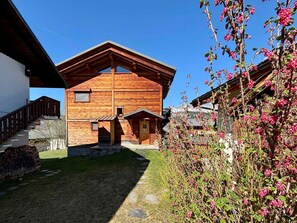 Un chalet en bois avec un toit en pente, un escalier en pierre et un petit jardin.