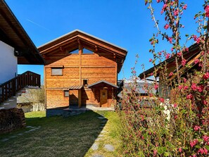 Eine Holzhütte mit geneigtem Dach, einer Steintreppe, die zum Eingang führt, und blauem Himmel.