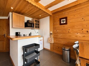 Eine Küche mit Holzausstattung, einer Mikrowelle, einer Kaffeemaschine und einem Mülleimer.