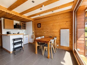 A kitchen with wooden cabinets, a microwave, and a refrigerator. There is a dining table with chairs and a cart. - Renovated duplex 4 pers, south balcony (Notre-Dame-de-Bellecombe)