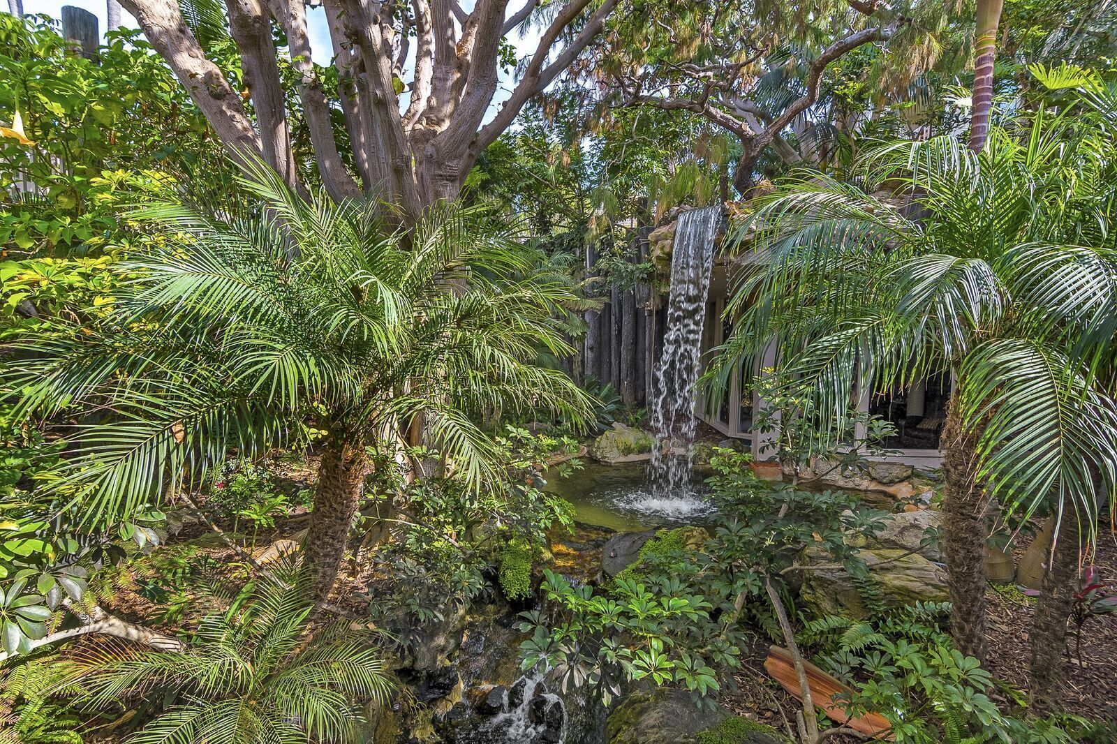 A lush garden with a waterfall and dense foliage.
