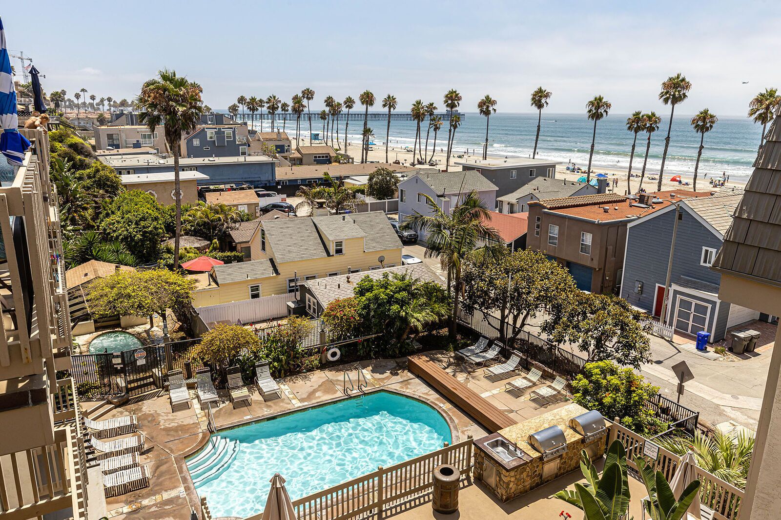 A residential area with a swimming pool, palm trees, and a view of the beach.