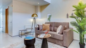 Ein modernes Wohnzimmer mit einer Couch, einem Couchtisch, einer Stehlampe und einer Zimmerpflanze.