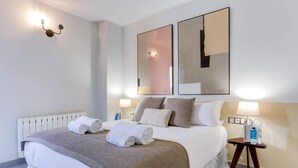 Ein Hotelzimmer mit einem großen Bett, zwei Wandlampen, einem Nachttisch mit einer Flasche und einem Spiegel.