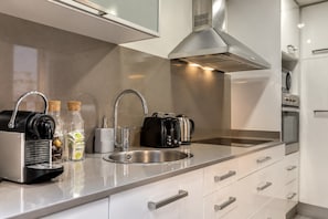A modern kitchen with stainless steel appliances, a sink, and a range hood.