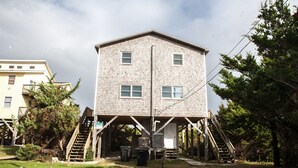 Um edifício de dois andares com um deque de madeira e escadas que levam a uma área coberta.