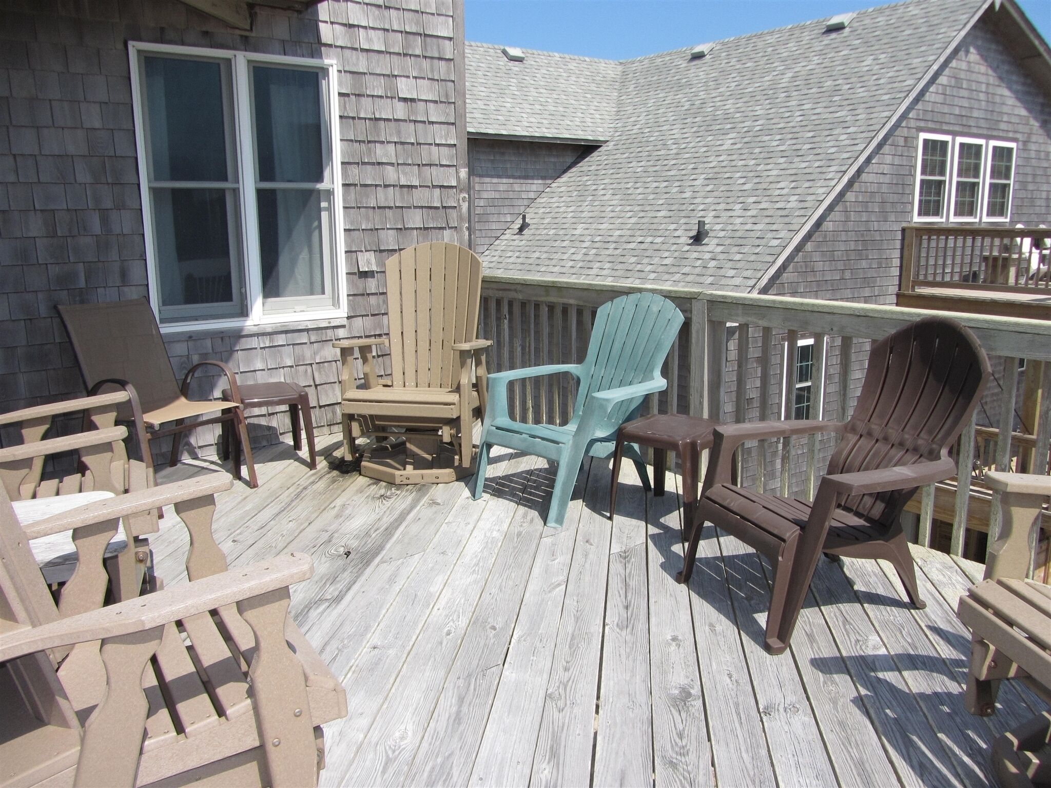 Une terrasse en bois avec des chaises Adirondack et une table.