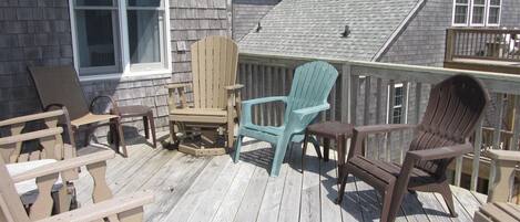 Une terrasse en bois avec des chaises Adirondack et une table.